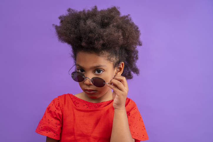 Ethnic kid girl looking camera lowering sunglasses