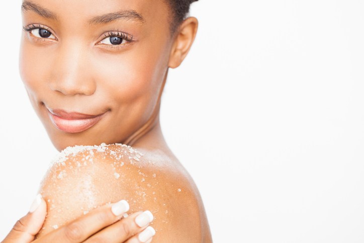 Woman exfoliating bare shoulder