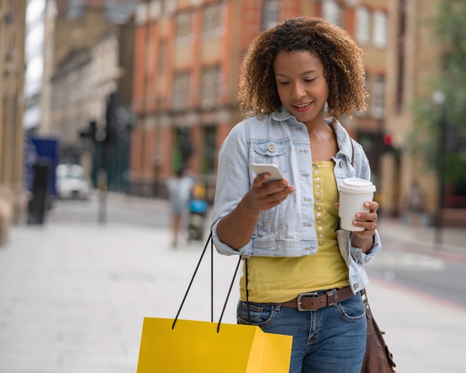 Shopping woman on the street using her mobile phone