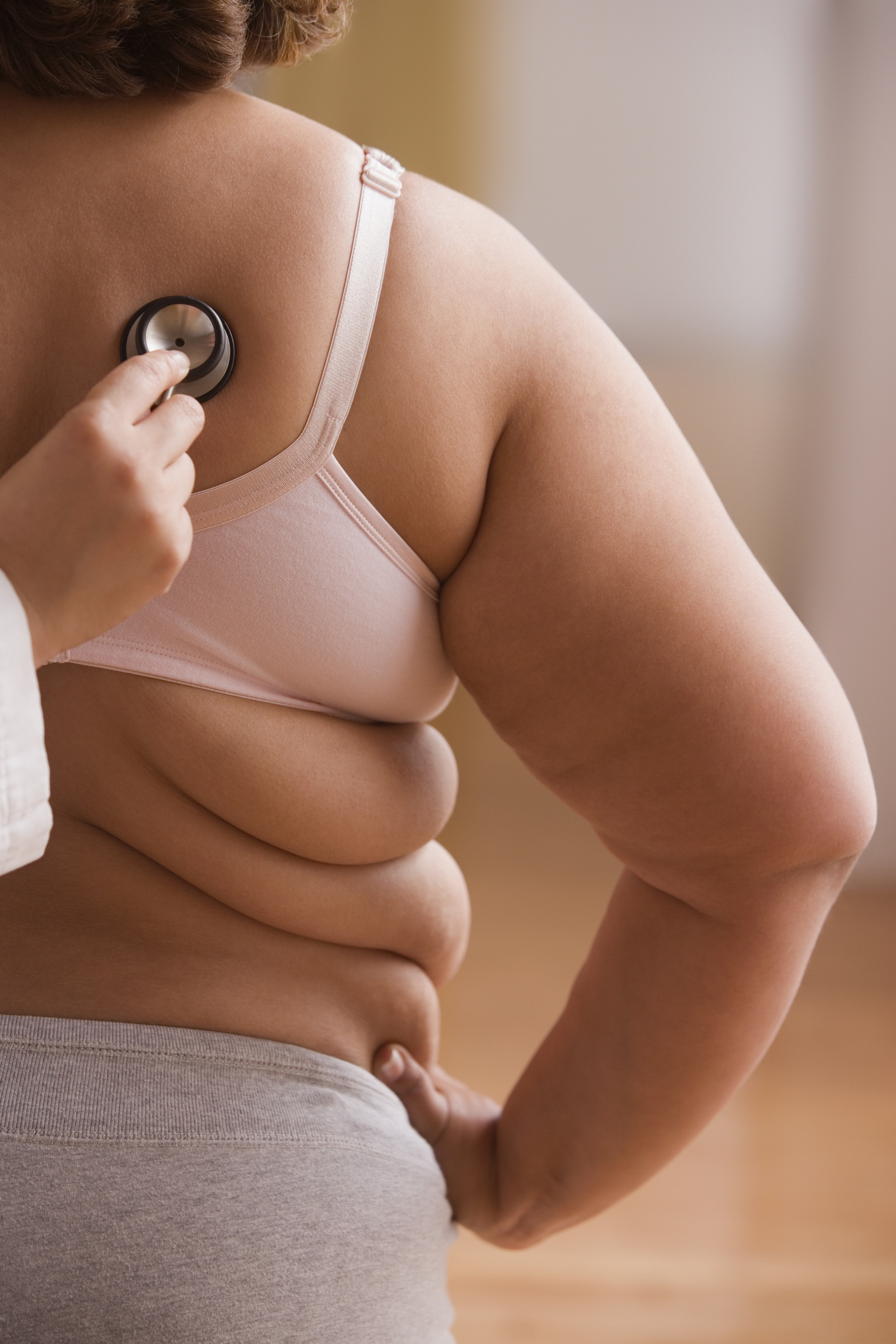 Overweight woman getting checked by doctor with stethoscope