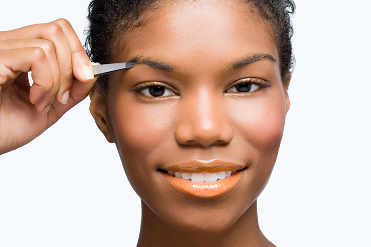 Young woman plucking eyebrows