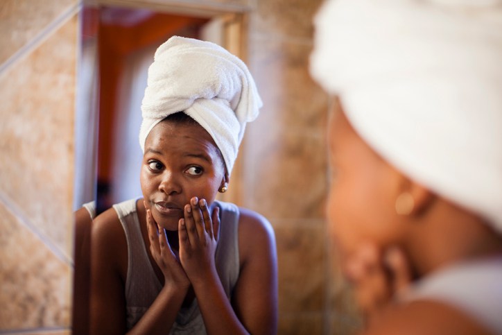 Young woman checking her skin in the mirror. Cape Town, Western Cape Province, South Africa