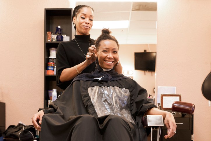 Female hairdresser combing woman's hair