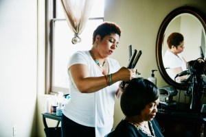 Salon owner straightening hair of client in salon