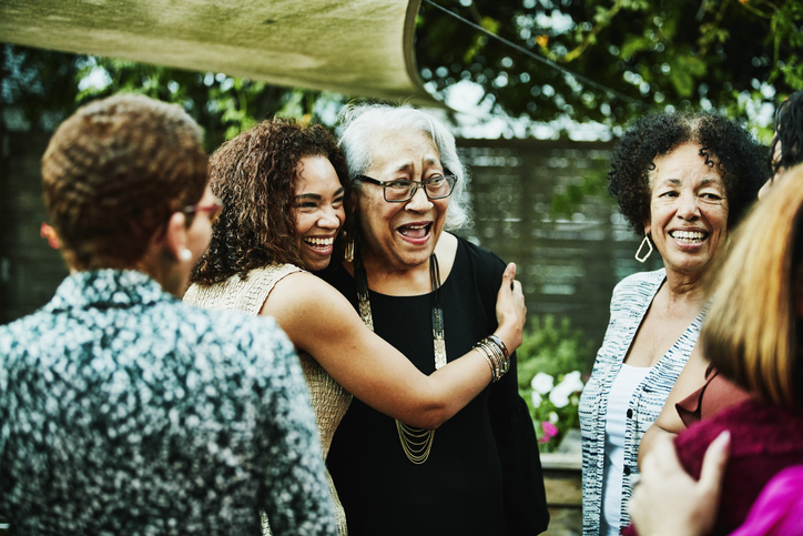 Mature daughter embracing senior mother after outdoor family dinner party