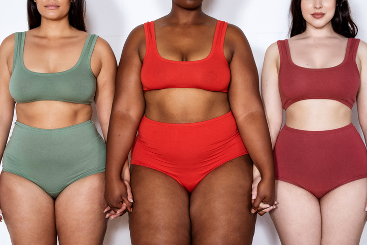 Plus size women in lingerie standing together holding hands