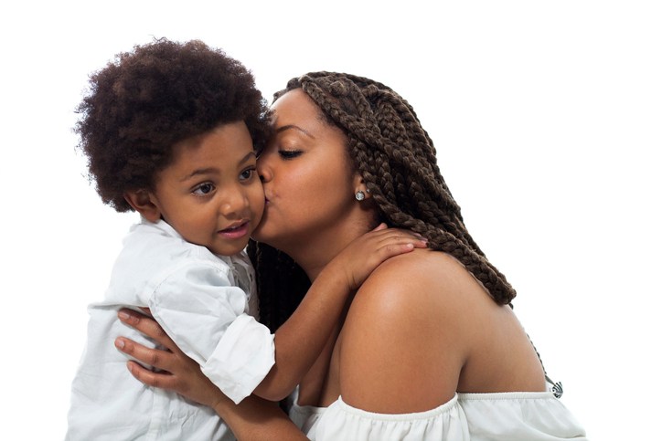 Black loving mother kissing her son on cheek