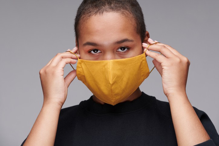 Portrait of young Black woman wearing yellow mask to protect herself against coronavirus