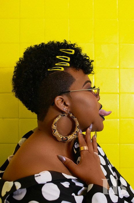 A photo silhouette of Amber Riley against a neon yellow and tiled wall.  