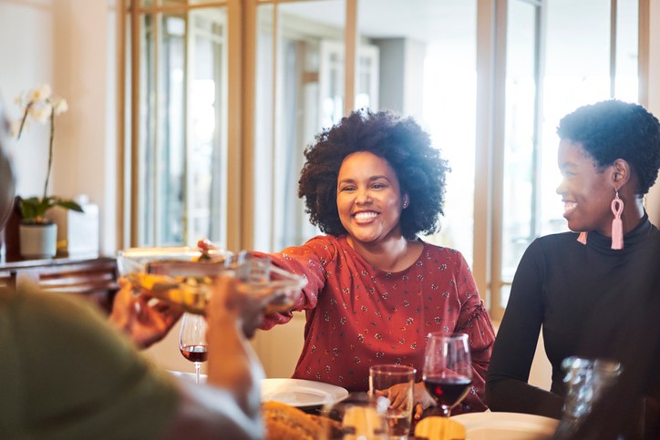 Smiling woman passing food to friend at table