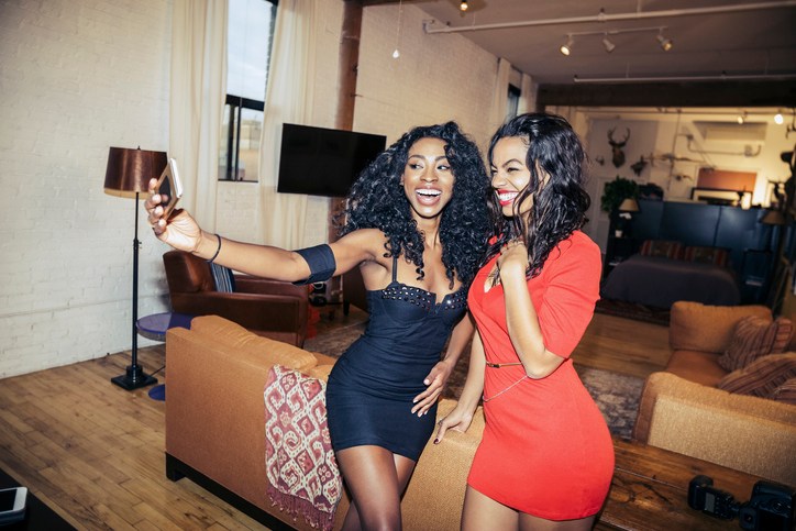 Happy young women taking selfie during party at home