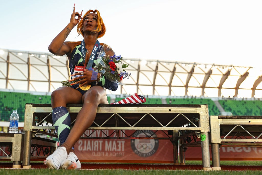 Sha'Carri Richardson sitting on a bench and staring at the sky.