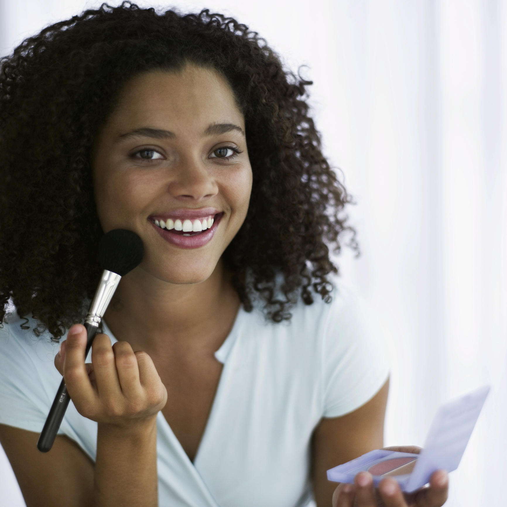 portrait of a young woman applying blush with a brush