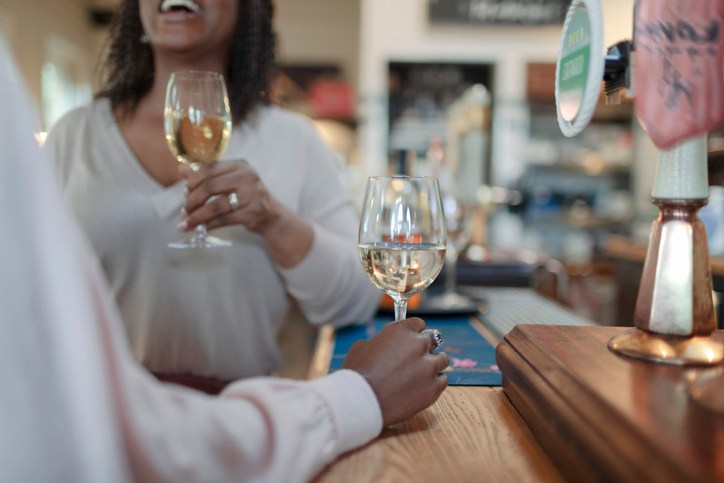 Women enjoying white wine at counter in pub