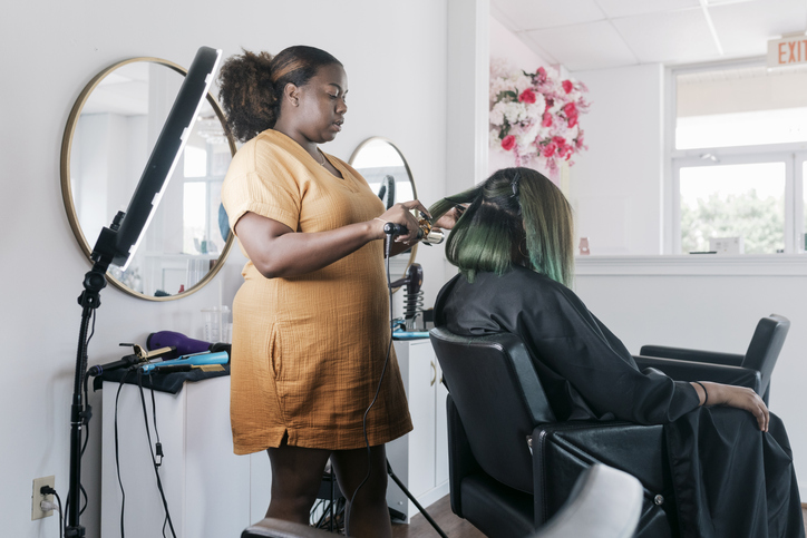 Hairdresser Using Curling Tongs On Client In Salon