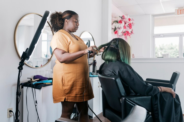 Hairdresser Using Curling Tongs On Client In Salon