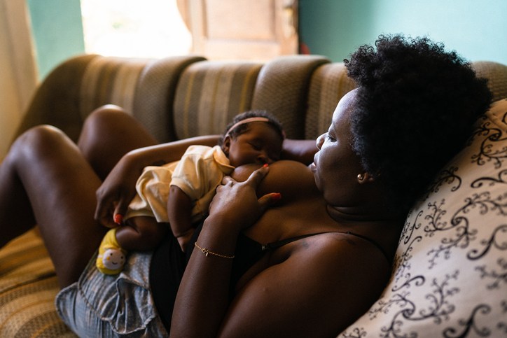black Mother breastfeeding lying on the couch