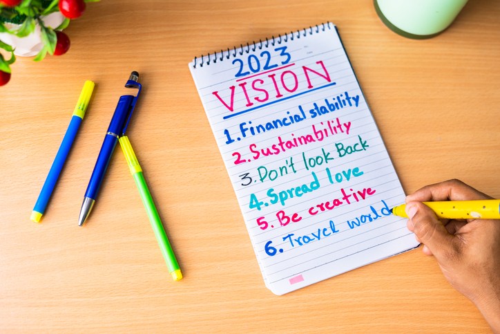 close up of hands adding making note of new year 2023 resolutions on dairy - concept of personal improvement or development and aspiration