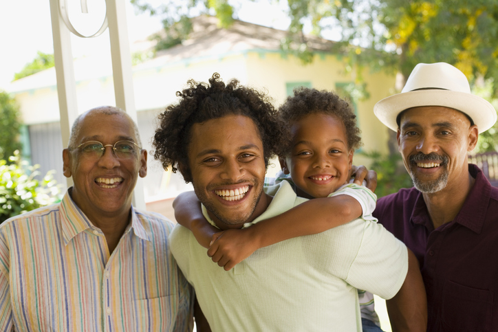 Man piggybacking young boy with two older men standing beside him