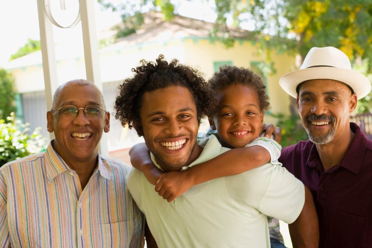 Man piggybacking young boy with two older men standing beside him