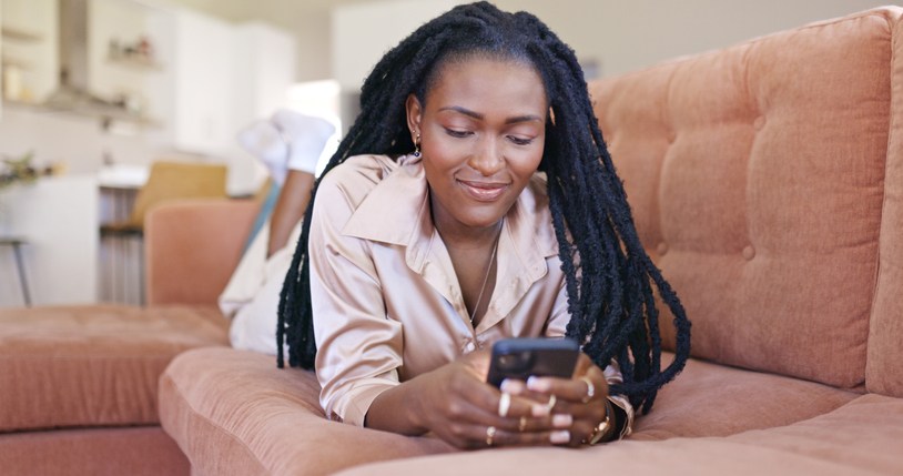 Young woman smiling while texting on her phone - 2023 party