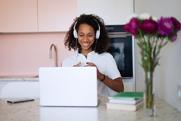 Beautiful young woman chatting online via video call on laptop.
