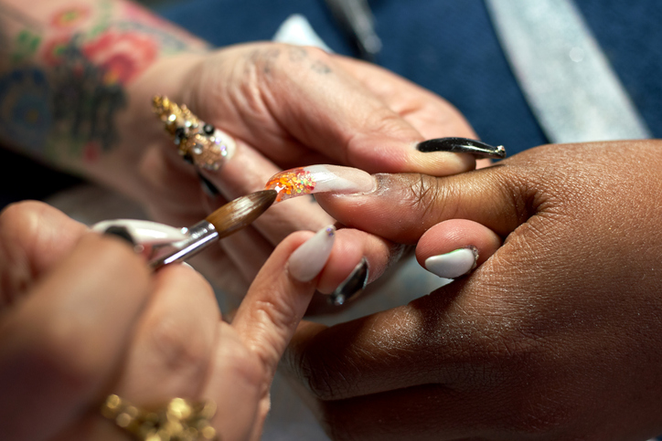 A close-up of a nail artist creating a chandelier nail manicure