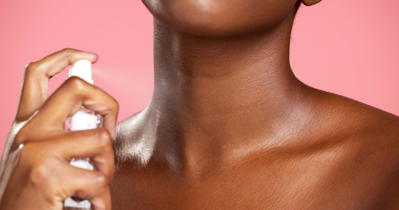 Person, hands and neck with spray for perfume, hygiene or cosmetics on a pink studio background. Closeup, model or fragrance with liquid mist, product or cologne for body essence, skincare or beauty