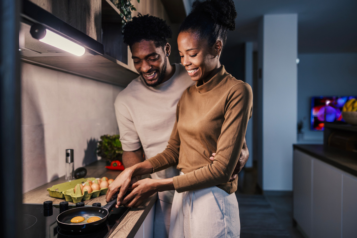 Happy black couple cooking breakfast in modern kitchen