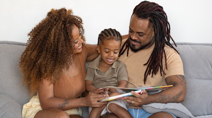 Afro family reading a book on the sofa