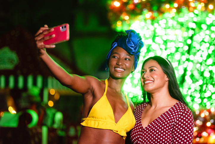 Diverse women friends taking selfie at nighttime holiday event