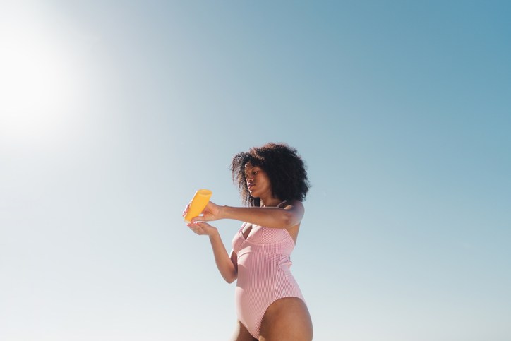 African American woman applying sunscreen at the beach