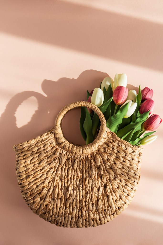 Tulip Bouquet in Straw Handbag. Stylish Spring Floral Composition on Pink Background