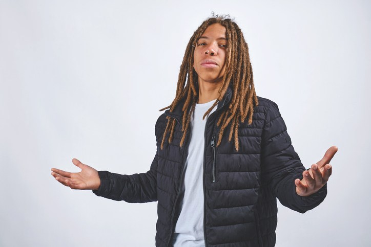 Young man with dreadlocks shrugging expressing confusion
