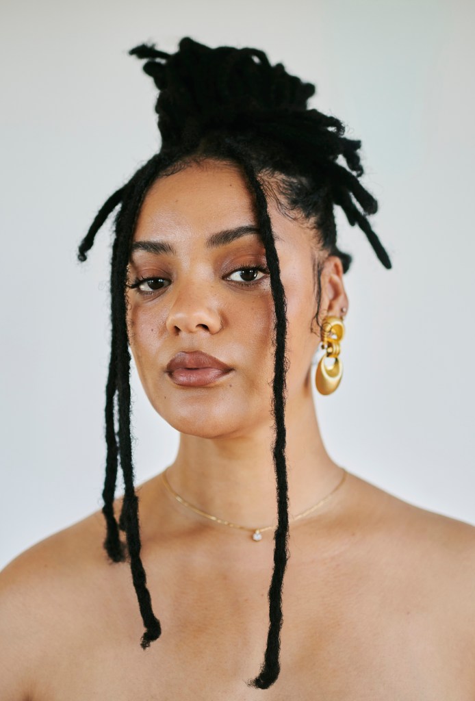 Confident Black Woman with Dreadlocks Wearing Gold Earrings and Necklace Portrait