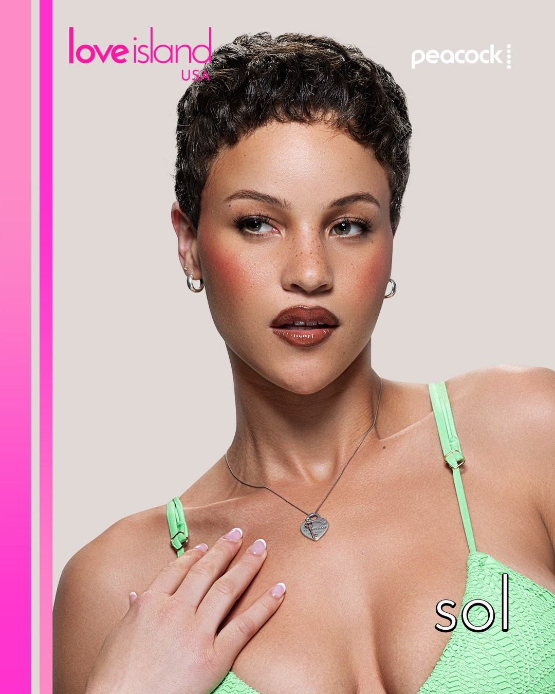 A woman with short dark hair wearing a green swimsuit top and necklace, looking directly at the camera against a pink background with "Love Island USA" and "Peacock" text.