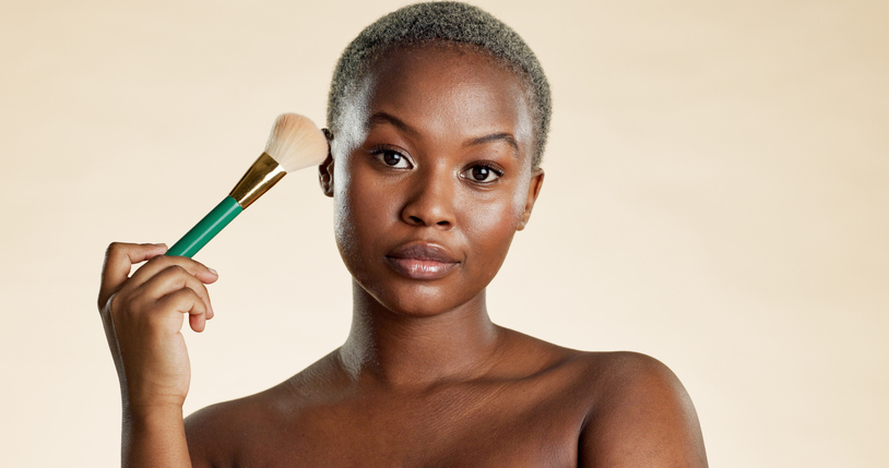 Brush, cosmetics and portrait of black woman with beauty, makeup or facial glow by studio background. Serious, foundation and African female person with tool for cosmetology with blush for self care.