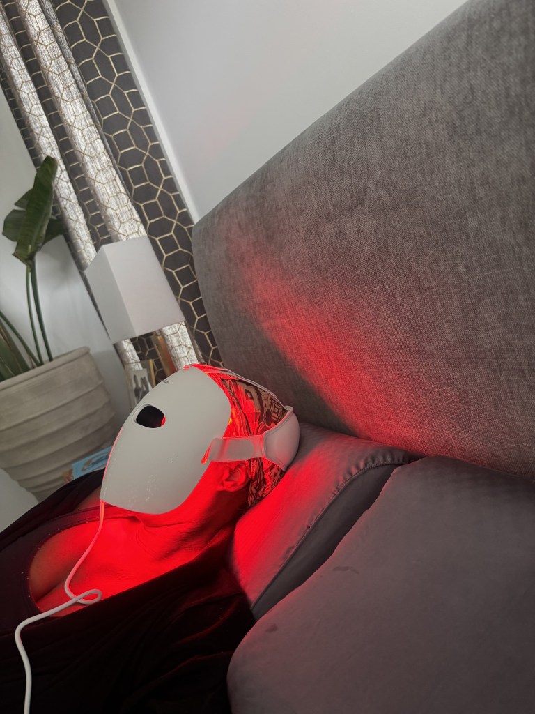 A red gaming headset with glowing red lights resting on a gray couch.