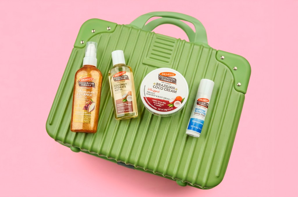 A green plastic suitcase containing various coconut-based beauty products, including a body oil, hydrating mist, and Brazilian cocoa cream.