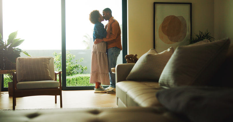 Love, kiss or couple in house with hug, partner affection or bonding together in connection. Tender, embrace or people with emotional security, romantic moment or commitment in healthy relationship.